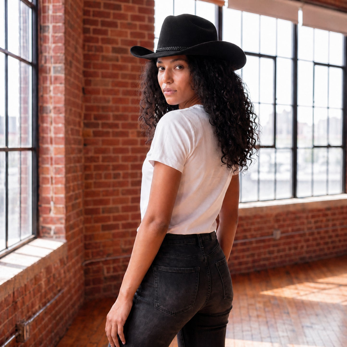 Back view of women’s white cotton t-shirt with relaxed fit styled with black cowboy hat