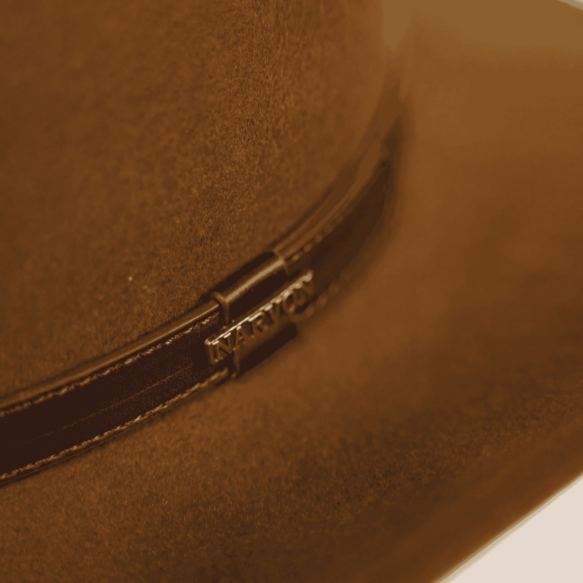 Close-up of brown Australian cowboy hat in wool felt with leather band and metal clasp detail