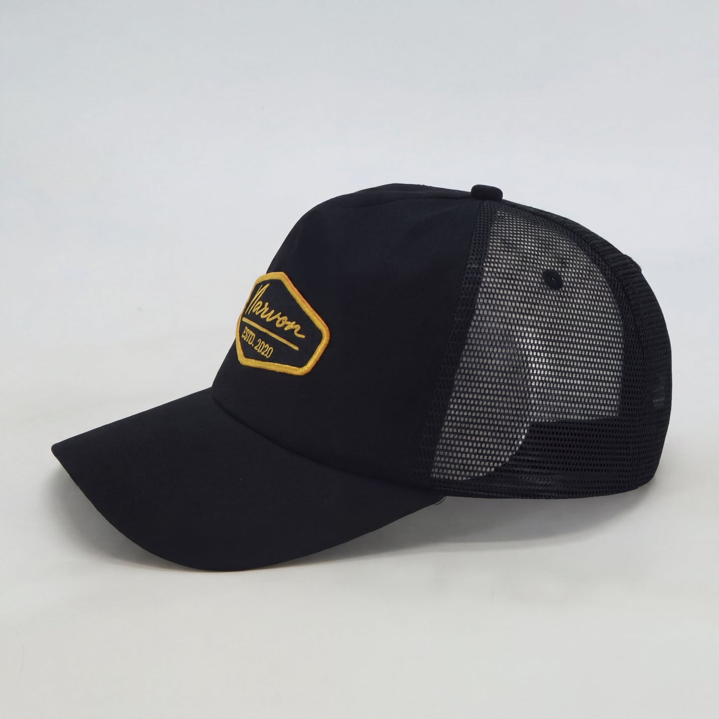 Side profile of men’s black trucker cap with mesh back and structured front panel