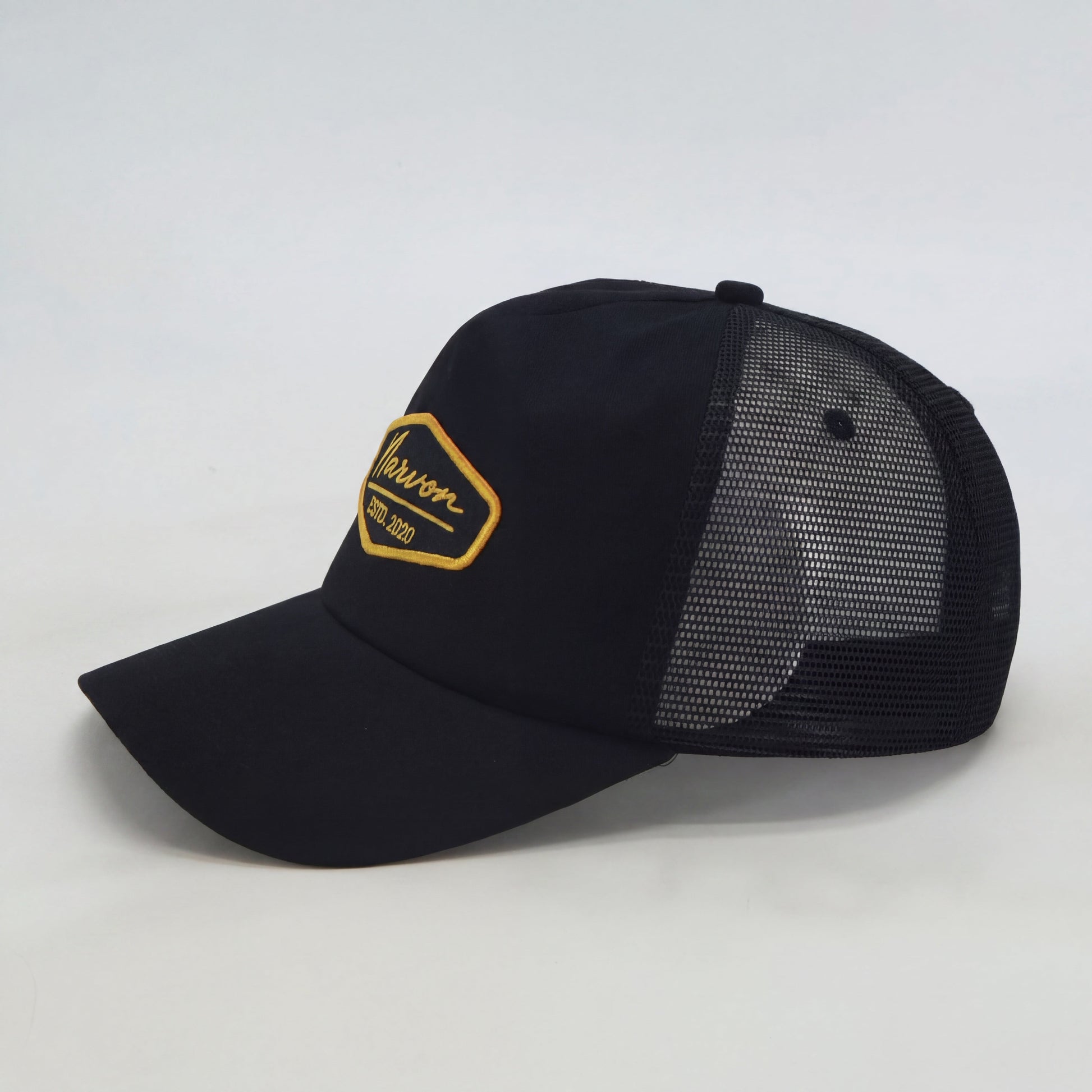 Side profile of men’s black trucker cap with mesh back and structured front panel