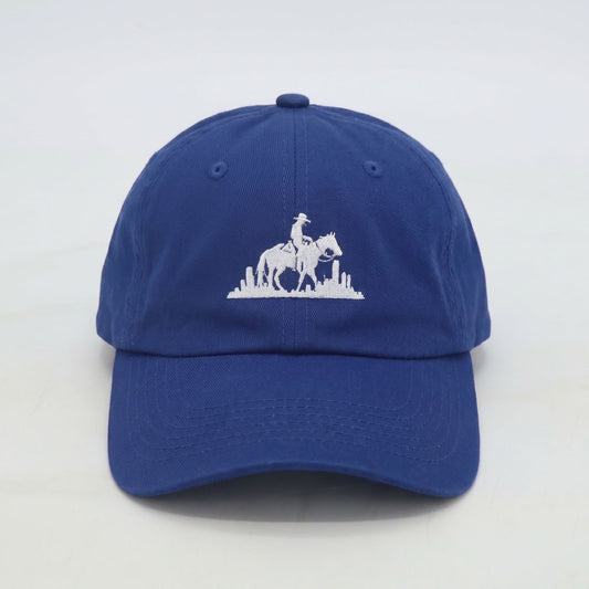 Front view of men’s royal blue dad cap with embroidered rider logo and city backdrop