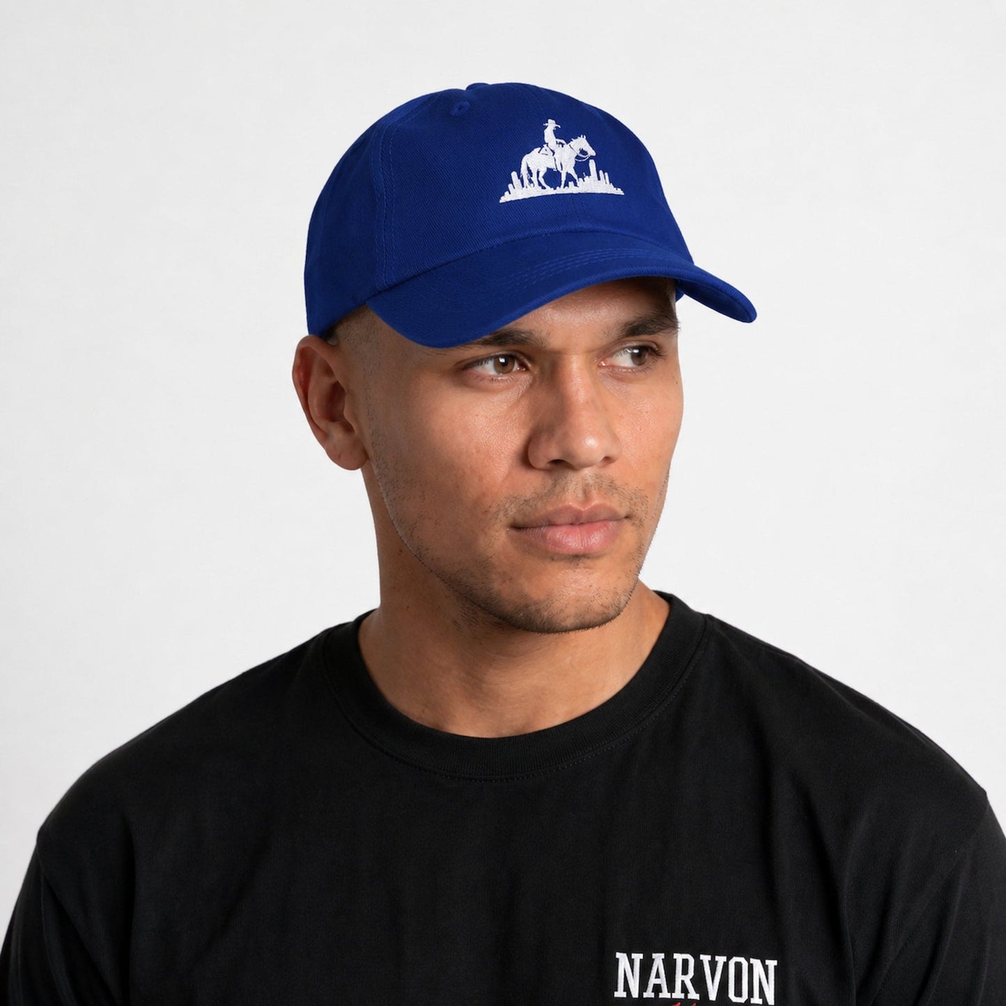 Men’s blue embroidered dad cap worn on model featuring rider logo with city design