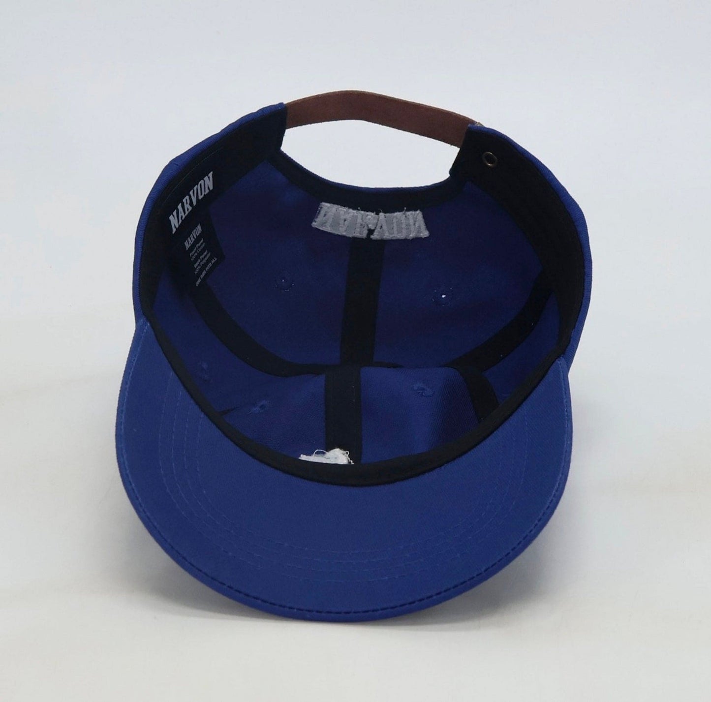 Interior of men’s dad cap showing cotton structure, stitching and leather strapback detail