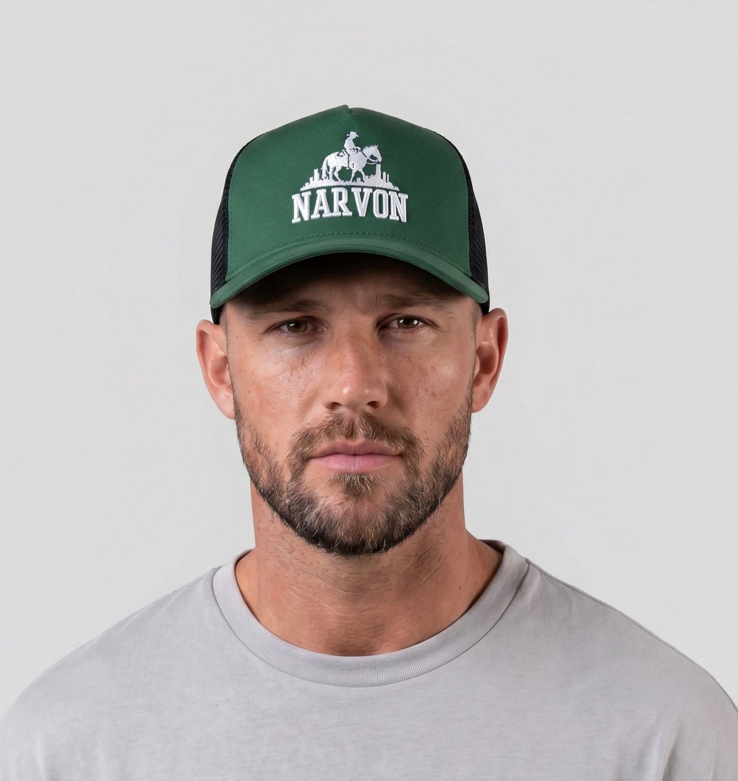 Men’s green trucker cap worn on model with embroidered logo and structured front panel