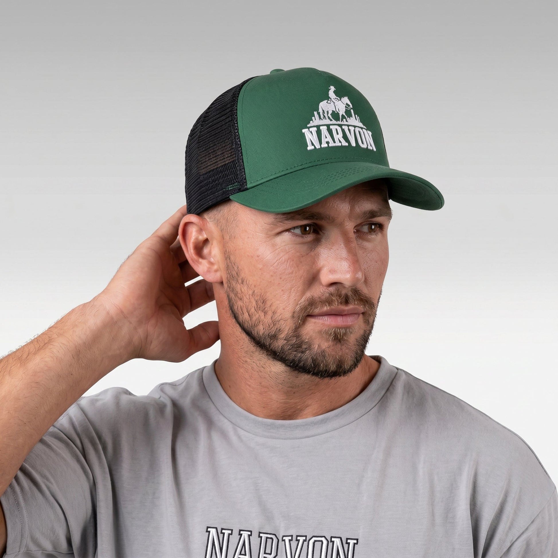 Men’s green trucker cap worn on model side angle showing mesh back and curved brim