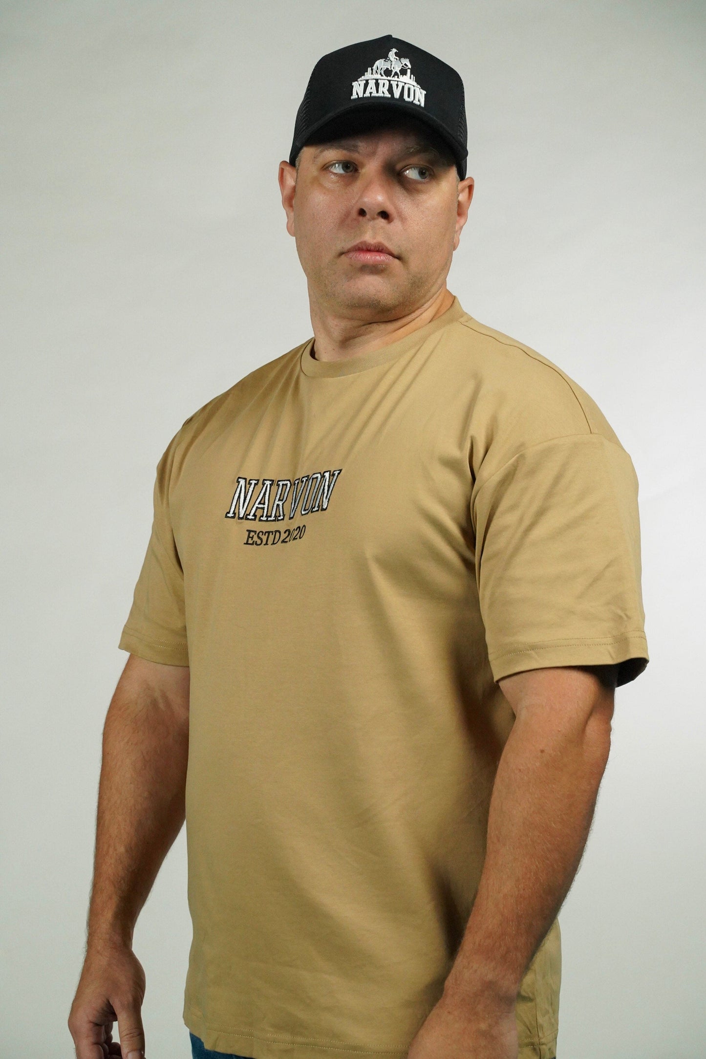 Man wearing a tan t-shirt with 'Narvon' branding and a black cap with 'Narvon' logo on a white background