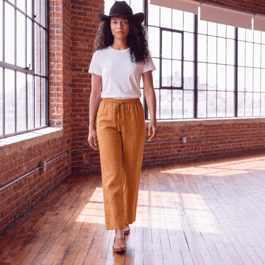 Woman walking in brown linen pants with wide leg and relaxed fit in a casual setting