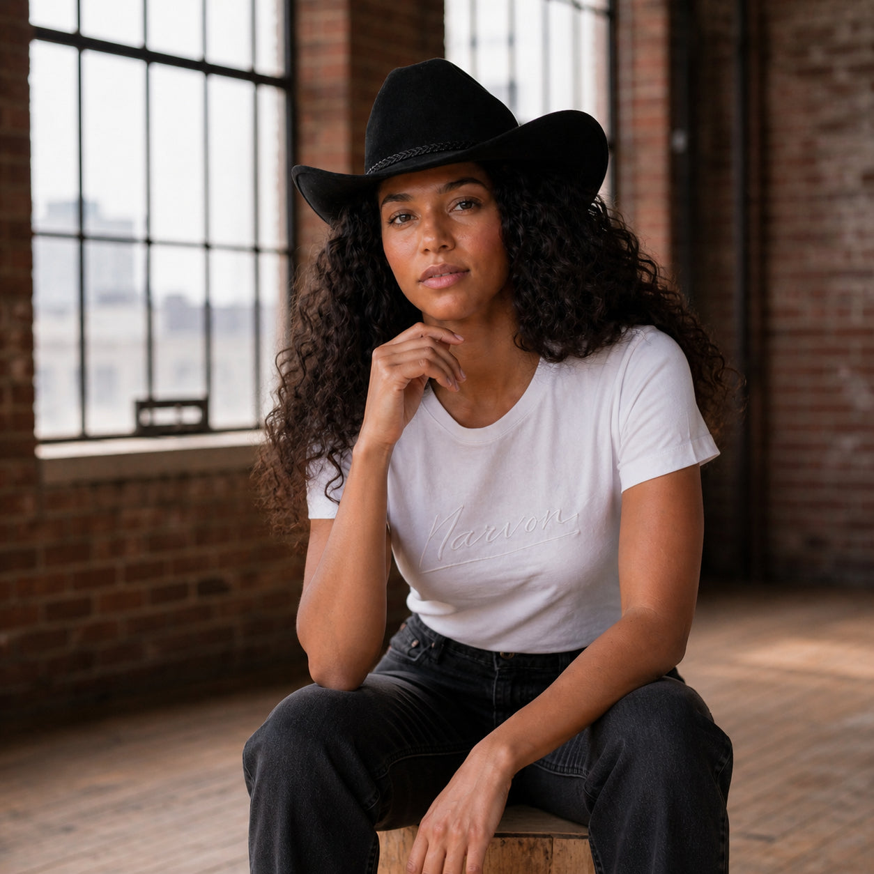 Woman wearing white cotton t-shirt with relaxed fit in a casual everyday outfit sitting indoors